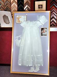 Shadow box frame with christening dress.